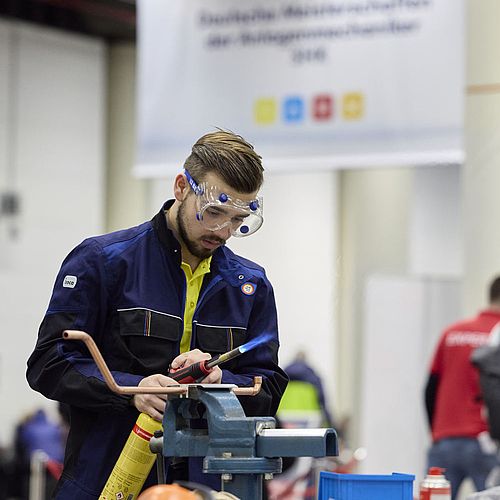 Ein Mann mit einer Schutzbrille arbeitet mit einer Brenngasflasche.