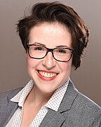 A Portrait of Ms. Katharina Fiegen. She has short brown hair, glasses and is smiling.